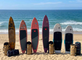 Planches et sacs de matériel alignés sur la plage