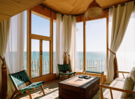 Salon sous charpente de bois, baies ouvertes sur le lagon