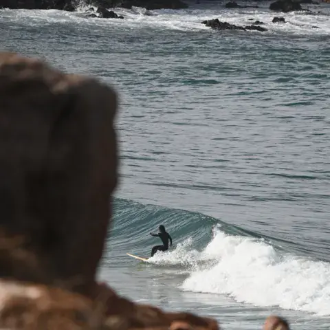 Un surfeur sous les falaises