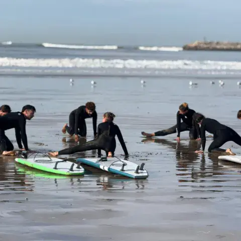 Cours de surf sur le sable, au bord de l'eau