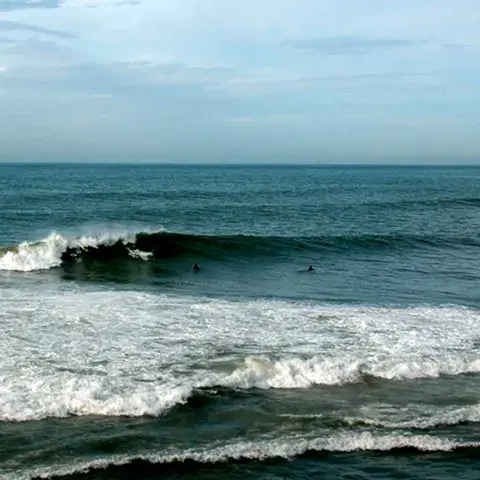 Séries de vagues sur le beach break, deux surfeurs au line-up