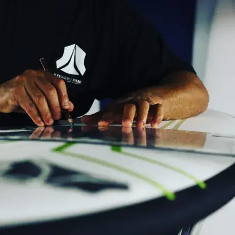 Alessandro Pierre traçant une planche dans son atelier de Seignosse