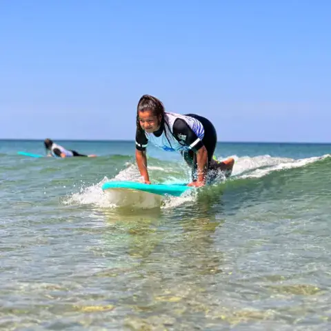Élève debout sur une planche lors d'un cours de surf