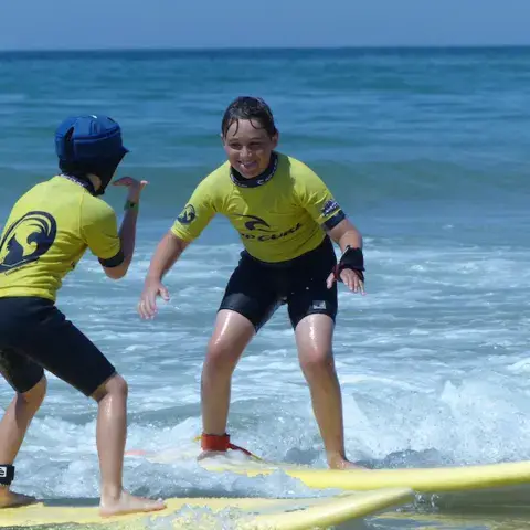 Deux enfants debout sur leur planche lors d'un cours de surf