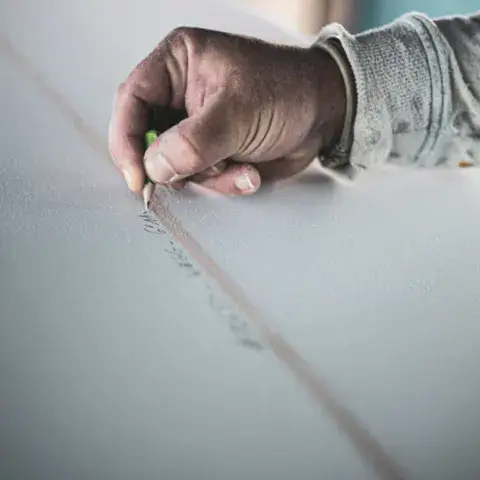 Tracé du stringer sur un pain de mousse à l'atelier Stark Surfboards