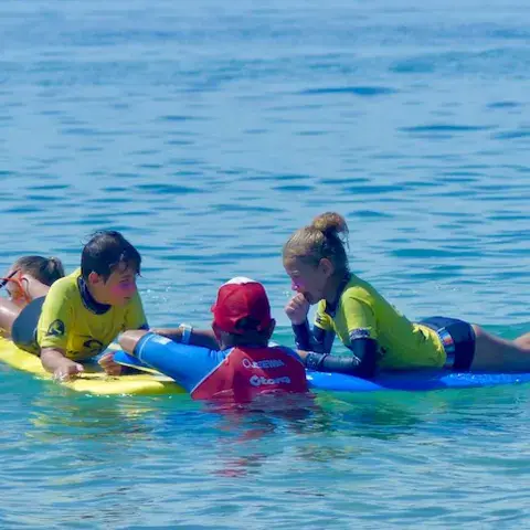 Élèves et moniteur allongés sur les planches dans l'eau