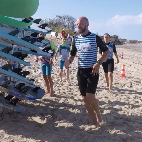 Moniteur et élèves avec leurs planches sur la plage