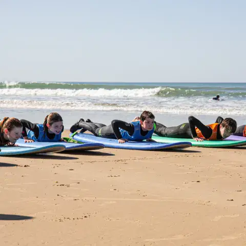 Groupe d'élèves allongés sur leurs planches pour un cours sur la plage
