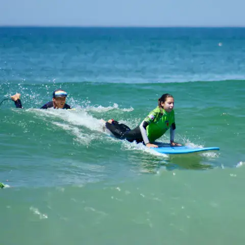 Élève allongée sur sa planche dans les vagues