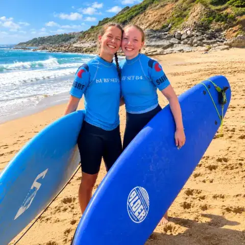 Deux élèves avec leurs planches sur la plage
