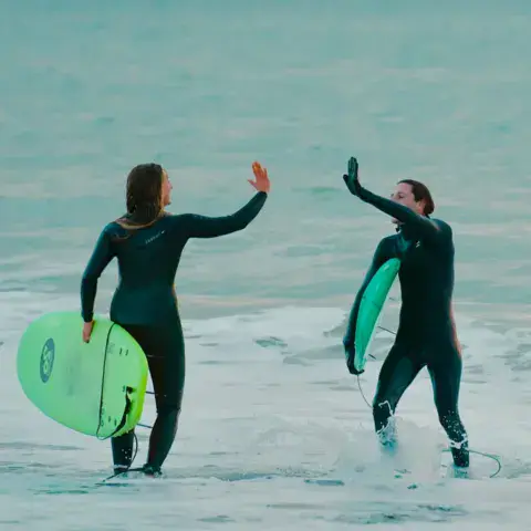 Surfeuses dans l'eau avec leurs planches