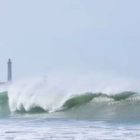 Vague déferlant près du phare, sur l'île de Ré