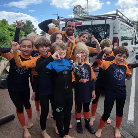 Groupe d'enfants en combinaison avant un cours de surf