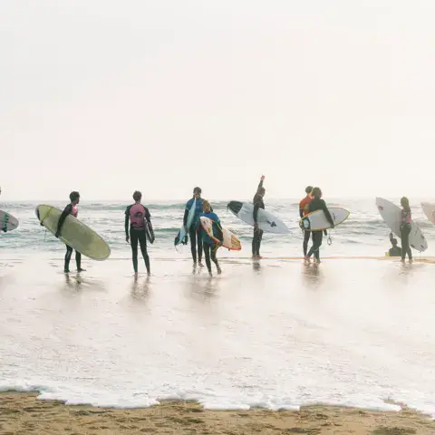 Surfeurs entrant dans l'eau sur la plage