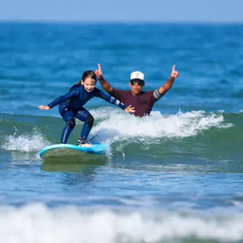 Un moniteur accompagne un enfant sur sa vague