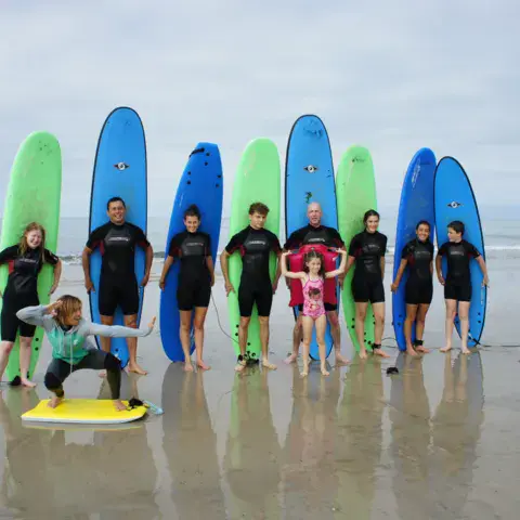 Groupe d'élèves avec leurs planches sur la plage
