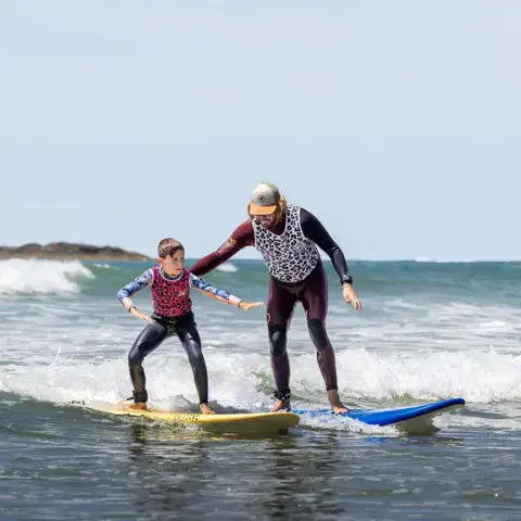 Moniteur accompagnant un élève dans les vagues