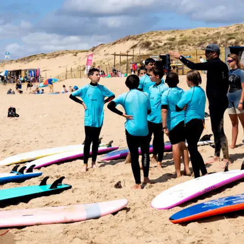 Groupe d'élèves avec leurs planches sur la plage