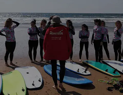 Groupe d'élèves avec leurs planches sur la plage