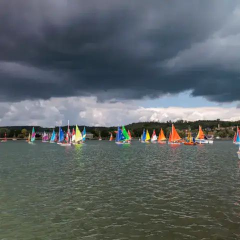 Flotte de voiliers sous un ciel orageux sur le plan d'eau