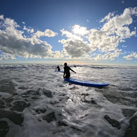 Surfeur entrant dans l'eau par temps froid