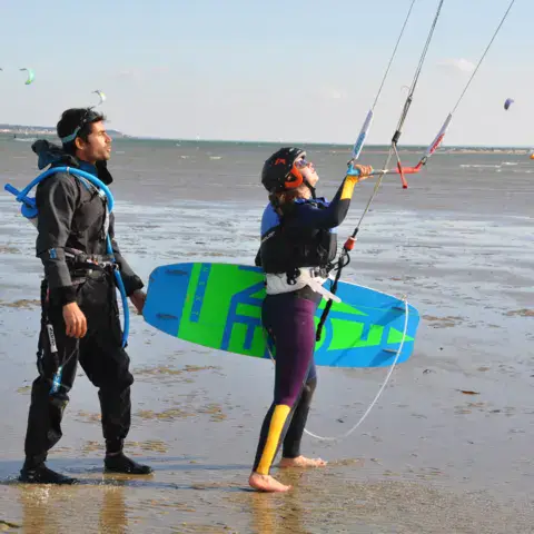 Moniteurs avec une aile et une planche de kitesurf sur la plage