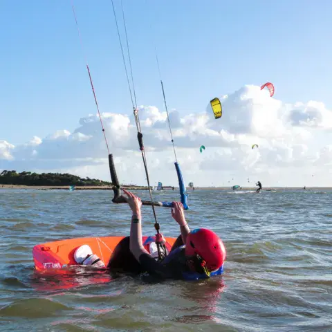Élève de kitesurf dans l'eau avec sa voile