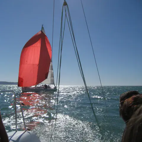 Voilier sous spinnaker vu depuis un bateau d'accompagnement