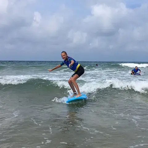 Élève de l'école debout sur sa planche dans les vagues