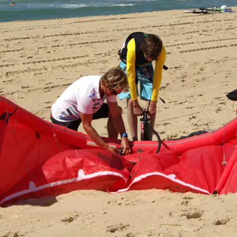 Préparation d'une aile de kitesurf sur la plage