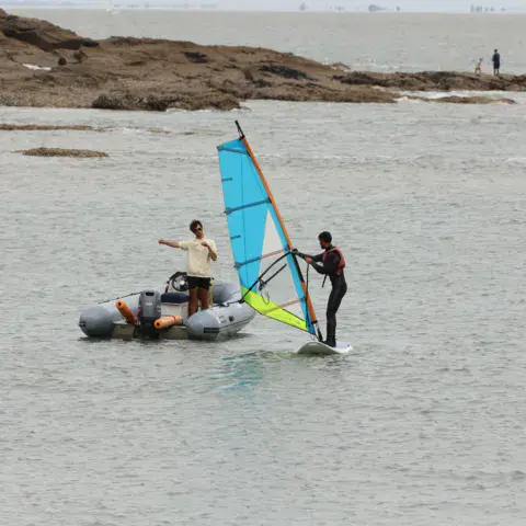 Initiation à la planche à voile près du bateau d'encadrement