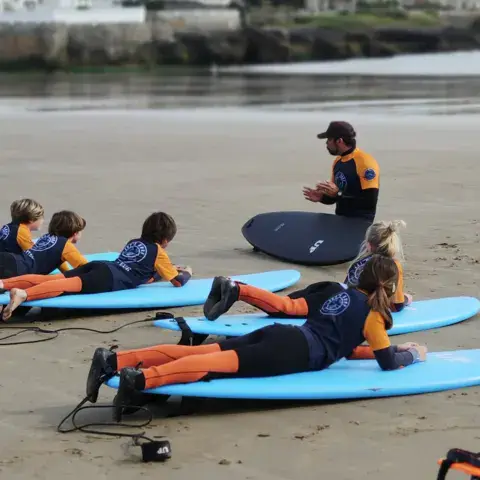 Enfants allongés sur leurs planches pendant un cours à la plage