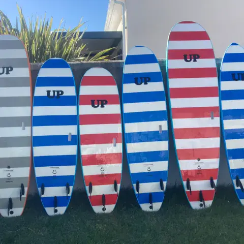 Planches de surf de l'école alignées contre le mur