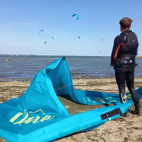 Moniteur et aile de kite posée sur le sable