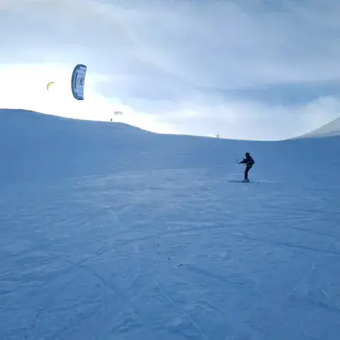 Élève en progression, kite en vol sur la neige