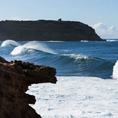 Vagues déferlant devant un cap rocheux