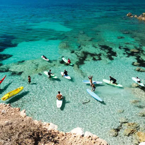 Pagayeurs en stand up paddle et kayaks dans une crique aux eaux claires
