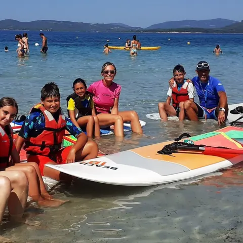 Groupe dans l'eau avec planches et voiles de windsurf école, baie d'Alghero
