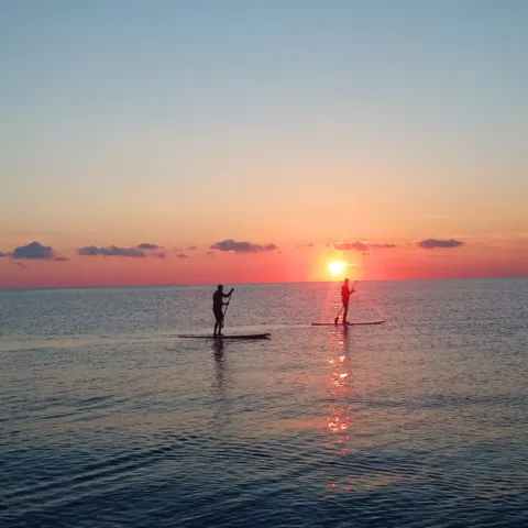 Deux pratiquants de stand up paddle au coucher du soleil