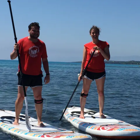 Deux pratiquants de stand up paddle en tee-shirt rouge sur la mer