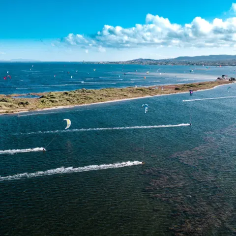 Kitesurfeurs sur l'eau plate de la lagune, vue de drone