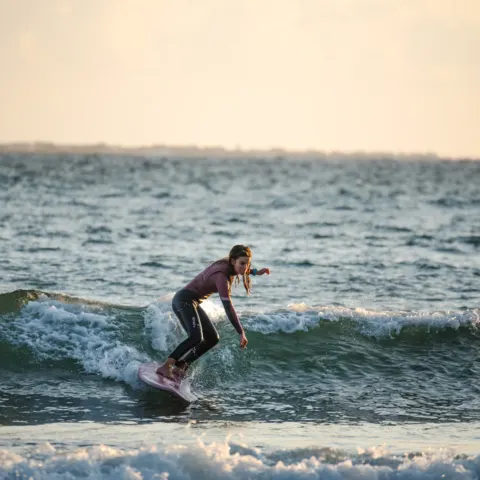 Surfeuse sur une petite vague au coucher du soleil