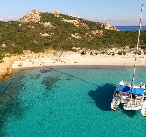 Catamaran de l'école au mouillage devant une crique