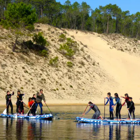 Groupe sur des SUP au pied d'une dune