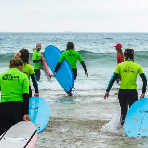 Élèves entrant dans l'eau avec leurs planches en mousse
