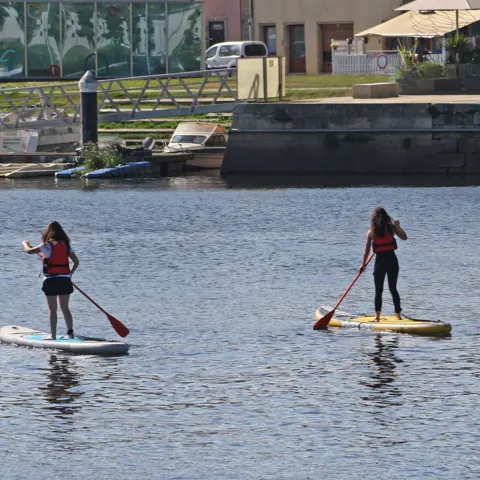 Deux pratiquantes de stand up paddle sur l'eau calme
