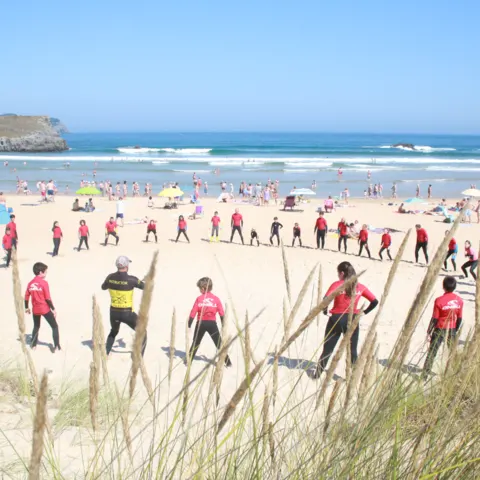 Groupe en combinaison rouge, échauffement sur la plage