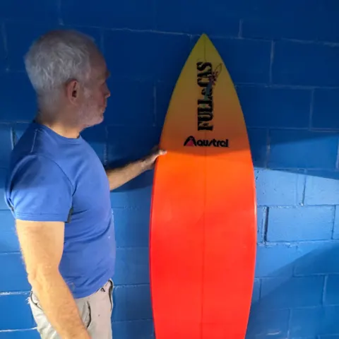 Planche rétro orange tenue par son shaper
