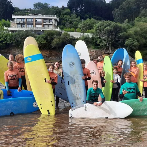 Groupe d'élèves avec leurs planches dans l'eau