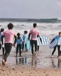 Groupe marchant vers la mer avec des planches